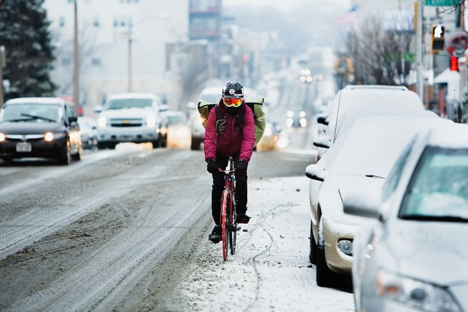 Cyclist Nick “Mint” Costanzo, a delivery man with Flavor Cycle, bikes down a snowy Milwaukee street. 