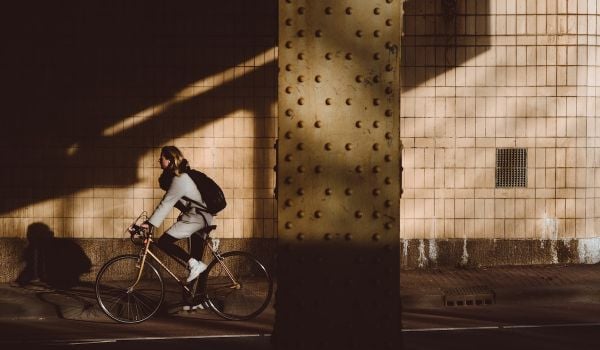 Person on a retro bike riding from the sunlight into the shadows.