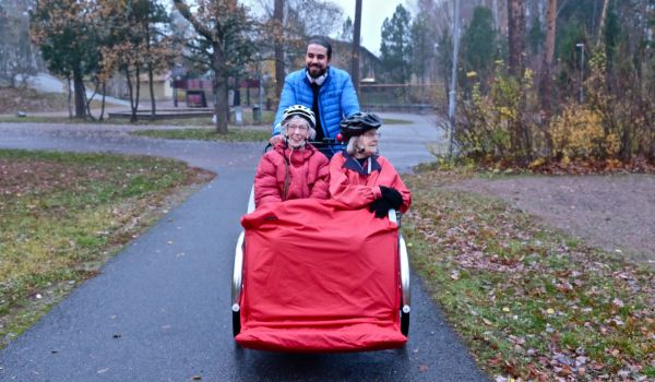 A volunteer taking two senior citizens on a bike ride through the forest in Sweden.