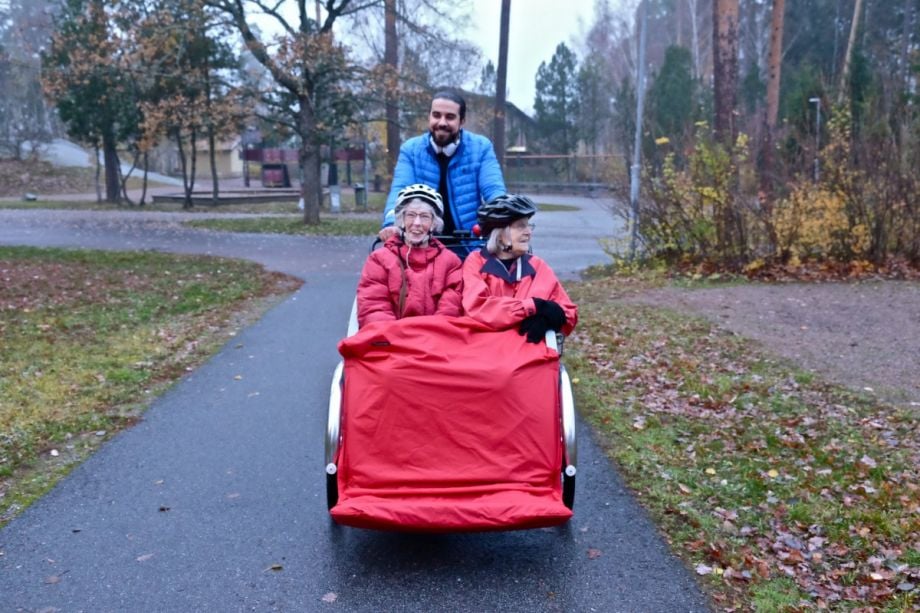 A volunteer taking two senior citizens on a bike ride through the forest in Sweden.