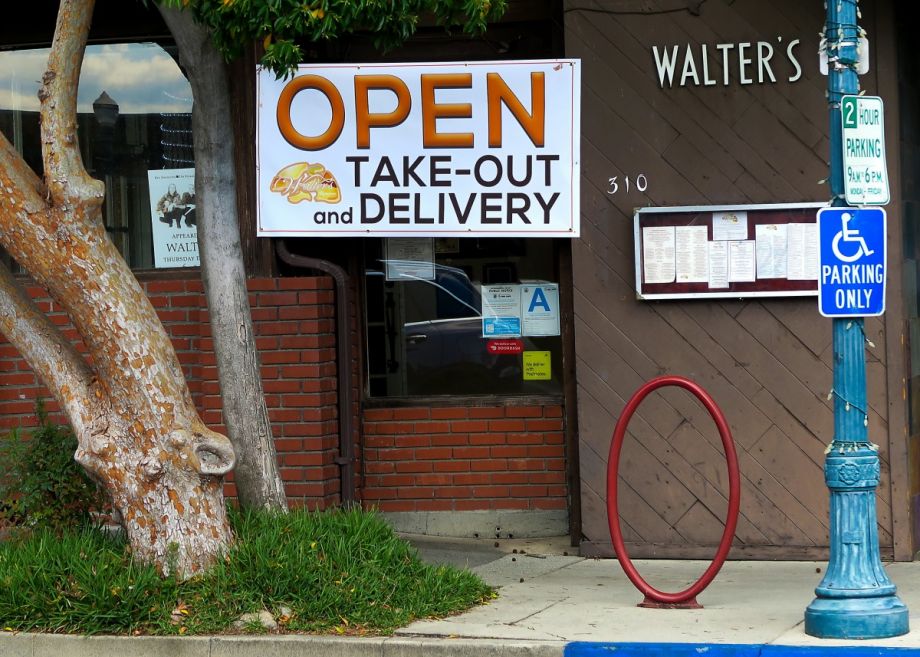a restaurant with a sign saying it is open for takeout and delivery only, due to the covid-19 pandemic