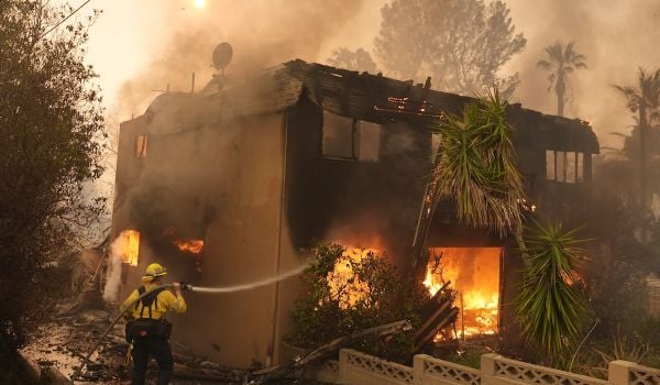 A firefighter tries to extinguish wildfire flames at a burning apartment building during the Eaton Fire, Jan. 8, 2025, in Altadena, California.