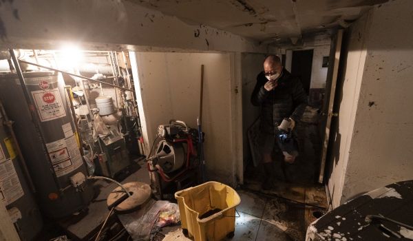 A man who gave his name as John helps to clean a friend's basement, Friday, Sept. 3, 2021, in Queens, New York. The area was flooded Wednesday as rain from the remnants of Hurricane Ida sent the New York City area into a state of emergency.