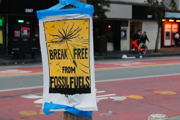 A black and yellow sign taped to a pole that reads, 'Break Free from Fossil Fuels'