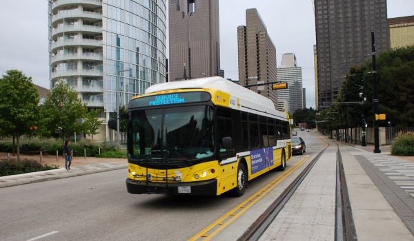Bus drives down street, next to light rail tracks