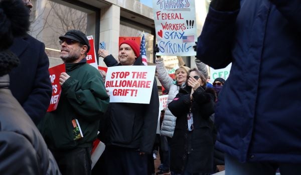 Protesters hold signs that read, 'Stop the billionaire grift' and 'Thanks federal workers! Stay strong.'