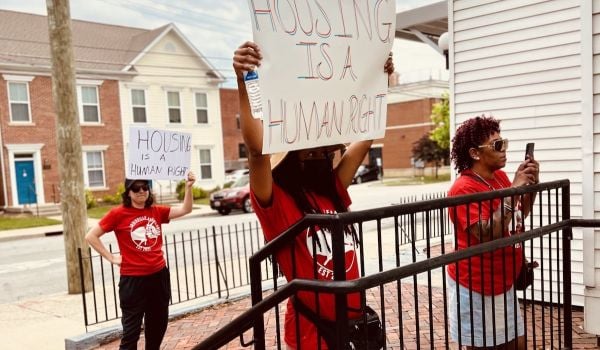 Group of people hold protest signs that read, 'Housing is a Human Right'