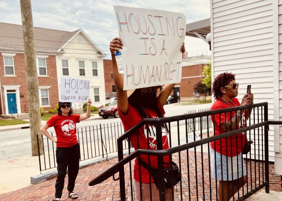 Group of people hold protest signs that read, 'Housing is a Human Right'