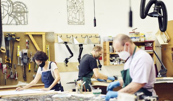 Three workers creating art at the stained glass studio