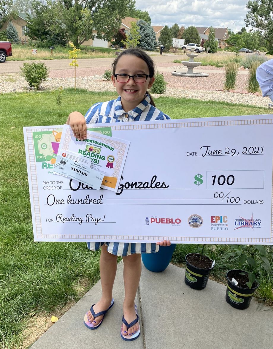Olivia with a giant check for reading and reviewing books