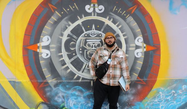 Oscar Sanchez stands in front of a mural