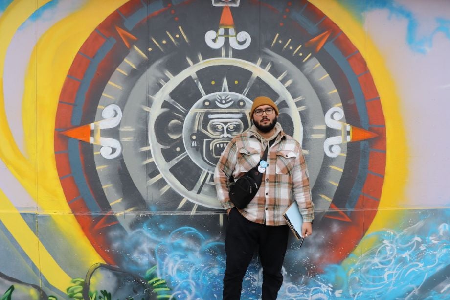 Oscar Sanchez stands in front of a mural
