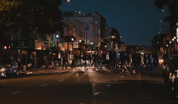 A group of people cross a street in Oakland at night