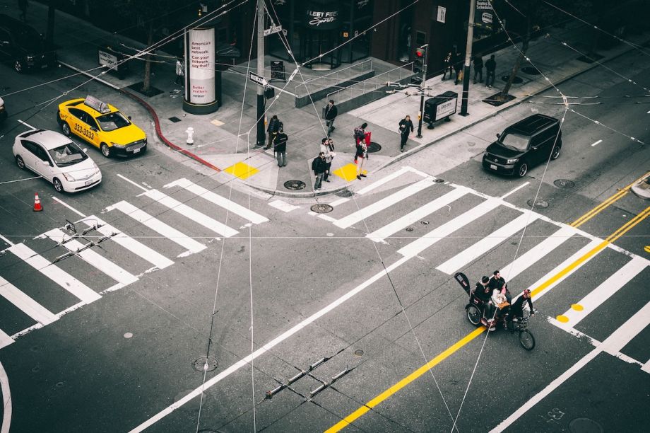 Intersection in San Fransisco where there are cars, a crosswalk, pedestrians and bikers