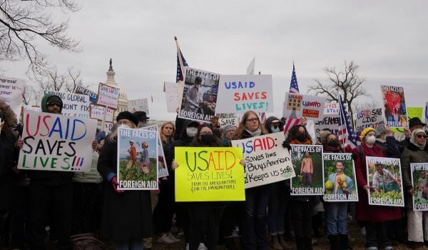 Protesters hold signs in support of maintaining USAID