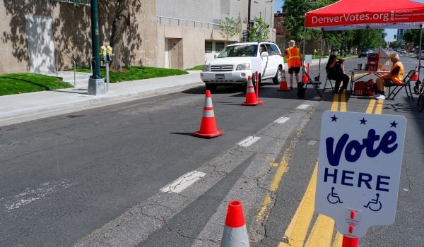 Person driving in a small white SUV drops off ballot in Denver, Colorado