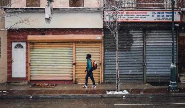 Person walks down a street in Philadelphia; there are flurries of snow in the air and on the ground