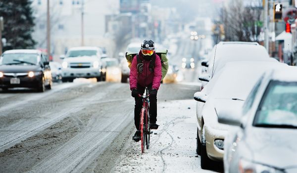 Cyclist Nick “Mint” Costanzo, a delivery man with Flavor Cycle, bikes down a snowy Milwaukee street.