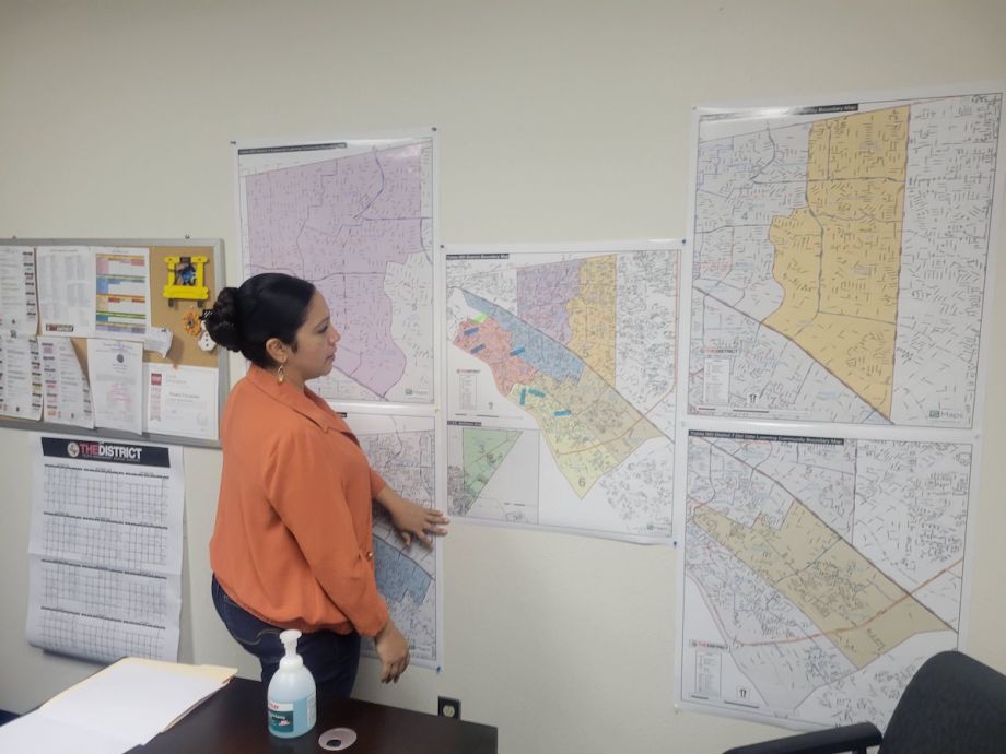 Rosario Fernandez looks at maps of school bus routes, which are posted on a wall