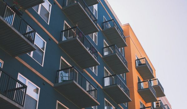 Looking up at a blue and orange apartment building with balconies
