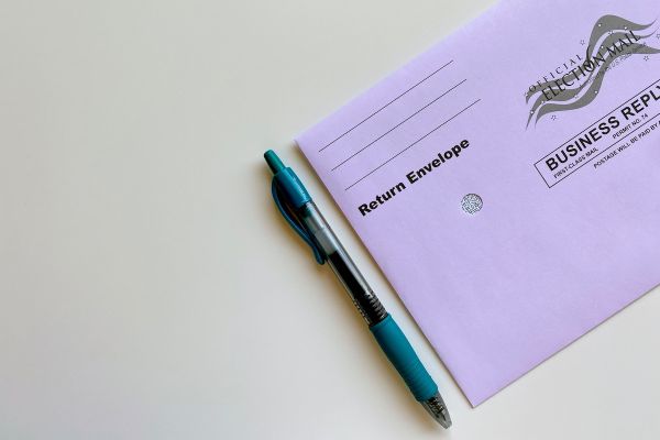A purple absentee ballot envelop with a pen next to it