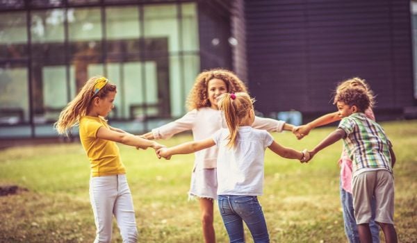 Group of children hold hands in a circle in schoolyard