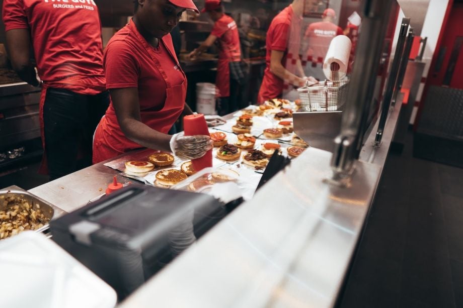 Fast food workers preparing meals. They're all wearing red t-shirts.
