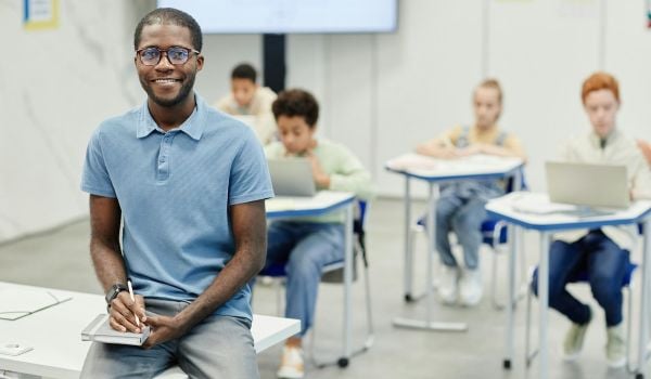 A Black man teaches in a classroom.