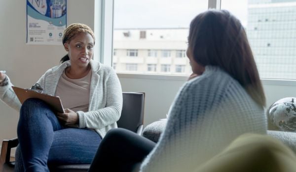 Stock photo of Black female therapist advising a client in an in-person therapy session