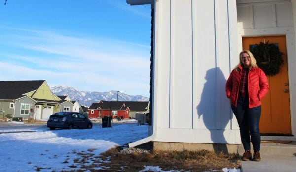 Woman standing in front of Montana home with a mountain view