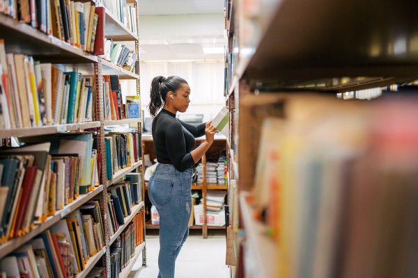 Patron stands in the aisle of a library and looks at books