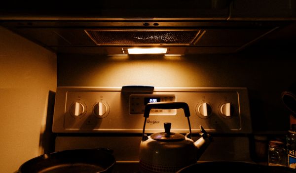 A kettle and pans sit on top of a stove with a night light on