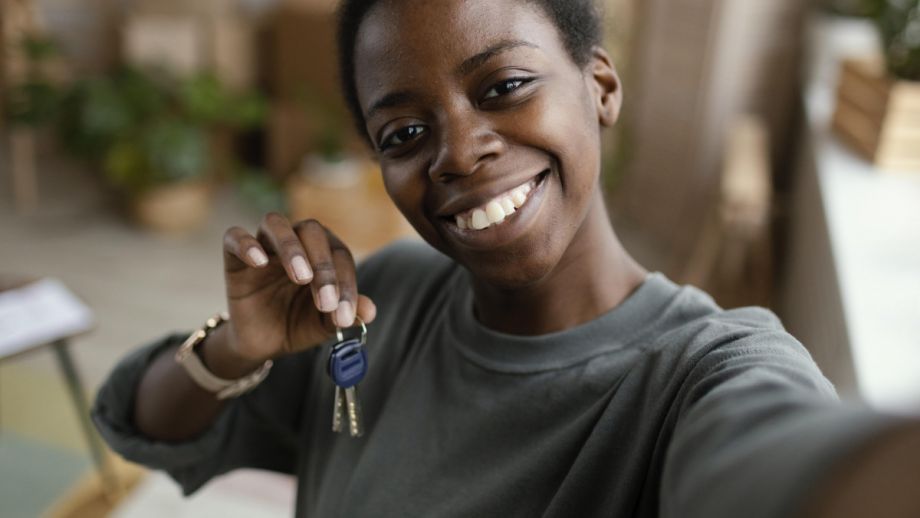 black woman holds up house keys