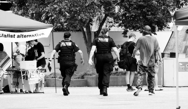 Police walking with people tabling with under a tent with a sign that reads, 'socialist alternative'
