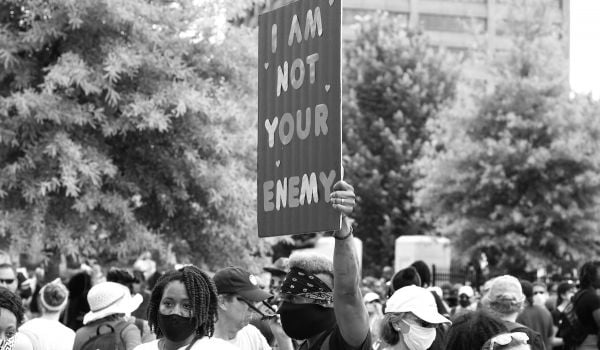 In a crowd at a protest, person holds a sign that reads 'I'm not your enemy'