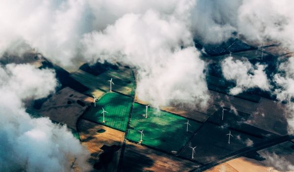 Wind turbines in a field can be seen through clouds, aerial view