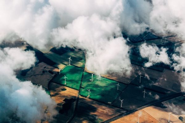 Wind turbines in a field can be seen through clouds, aerial view